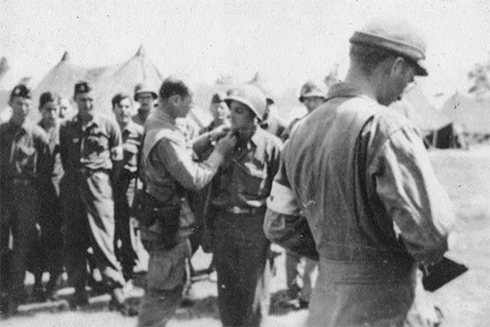 Ceremony during which Captain J. J. Belden gets promoted to the grade of Major. The  Officer is Major General Matthew B. Ridgway, CG, 82d Airborne Division. The date must be early July 1944 (J. J. Belden served from 7 May 1942 until 5 December 1945 in the Zone of Interior, Mediterranean Theater, European Theater, and eventually in Japan).