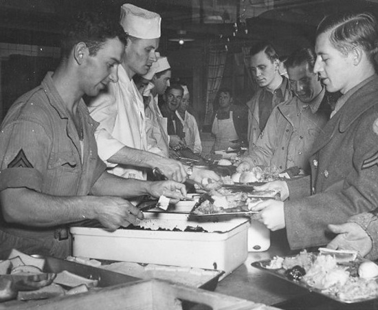 23 November 1944, GIs enjoy Thanksgiving Dinner somewhere in a barn, a requisitioned, or an abandoned building. It was always a treat to obtain some real hot chow with all the trimmings, and many a soldier ate until he got sick ... unfortunately many others had to do with cold food outside ...