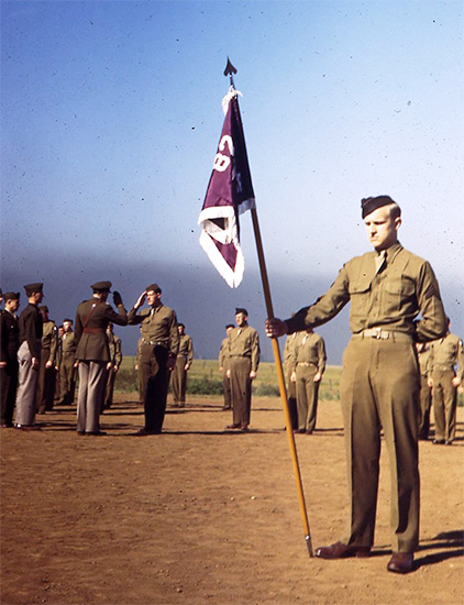 Formation, Camp White, Medford, Oregon. A Corporal holds the unit's Guidon, while the Officer saluting in the the background (left) is Major Q. Nicola, MC, O-338283, the organization's Executive Officer.