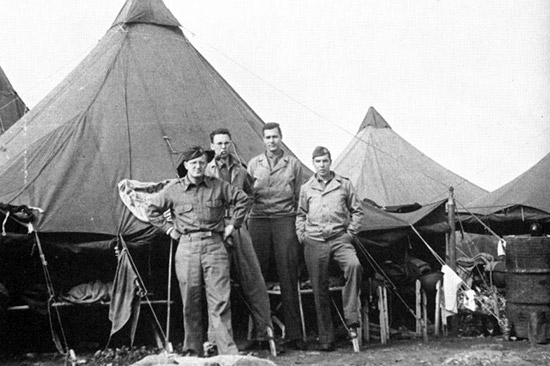 Four members of the 45th General Hospital pose for a photograph in front of their Pyramidal Tent during the bivouac at "Goats Hill", en route to Naples, Italy.