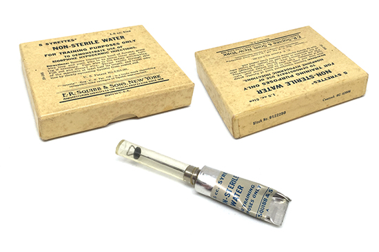 An illustration showing the non-sterile water 5-pack of Syrettes (Item # 9122250), as used for the training of medical personnel in the administration of Morphine Tartrate using the Syrette.
