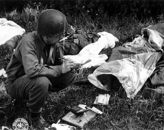 Omaha Beach, collection point, Sergeant Peter F. Slusarczyk, 603d QM GR Co, verifies and completes the EMT of a dead soldier, June 12, 1944, prior to preparation for temporary burial at Sainte-Mère-Eglise Cemetery.