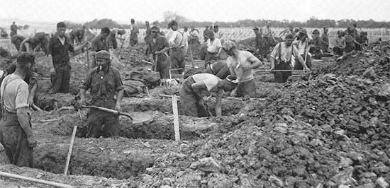 German PWs at work digging graves at the Sainte-Mère-Eglise Cemetery No. 1, Normandy, June 9, 1944.