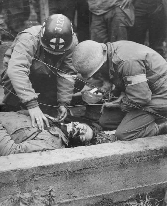 Somewhere in France 1944. First aid being applied to a wounded GI in the field, prior to evacuation.