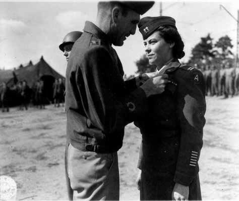 Colonel George McCoy, Commanding Officer, 12th Evacuation Hospital, awards the Legion of Merit to Captain Lillian Carter, ANC Chief Nurse, July 29, 1945, during formation and parade, somewhere in Germany.