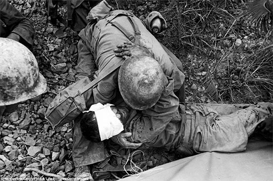 1943; somewhere  in the South Pacific Area. Medical Department personnel comfort a wounded soldier.