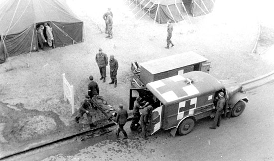 A patient arrives at the 25th General Hospital, Tongres, Belgium. The soldier is transferred from the 3/4-ton ambulance to the Receiving by PW litter bearers.  