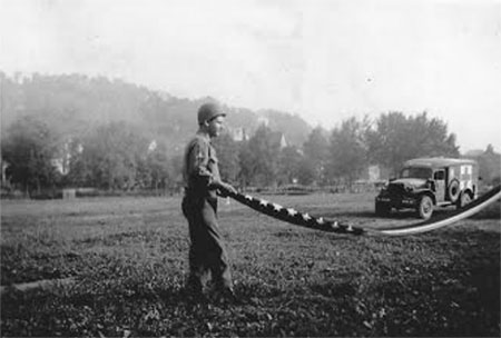 Cpl. John Wood folds the American flag for the first time on German soil. A Dodge Ambulance is (assigned to the 263d Med Clr Co) is clearly visible in the background. Photograph taken on 1 June 1945.Courtesy  Christine Smith