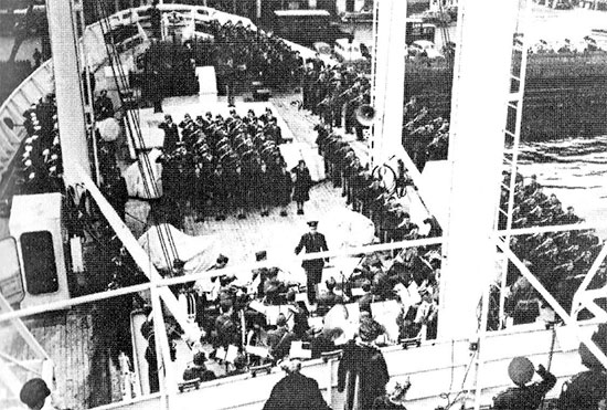 Partial view of the official Commissioning, taken 16 March 1945. Foredeck USAHS Louis A. Milne; the band is playing the national anthem while all personnel stand at attention and salute.