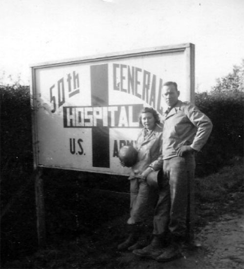 First Lieutenant Frances Cardozo Jones and her husband Earl pose for the camera in front of the 50th General Hospital's sign in Carentan, France. 